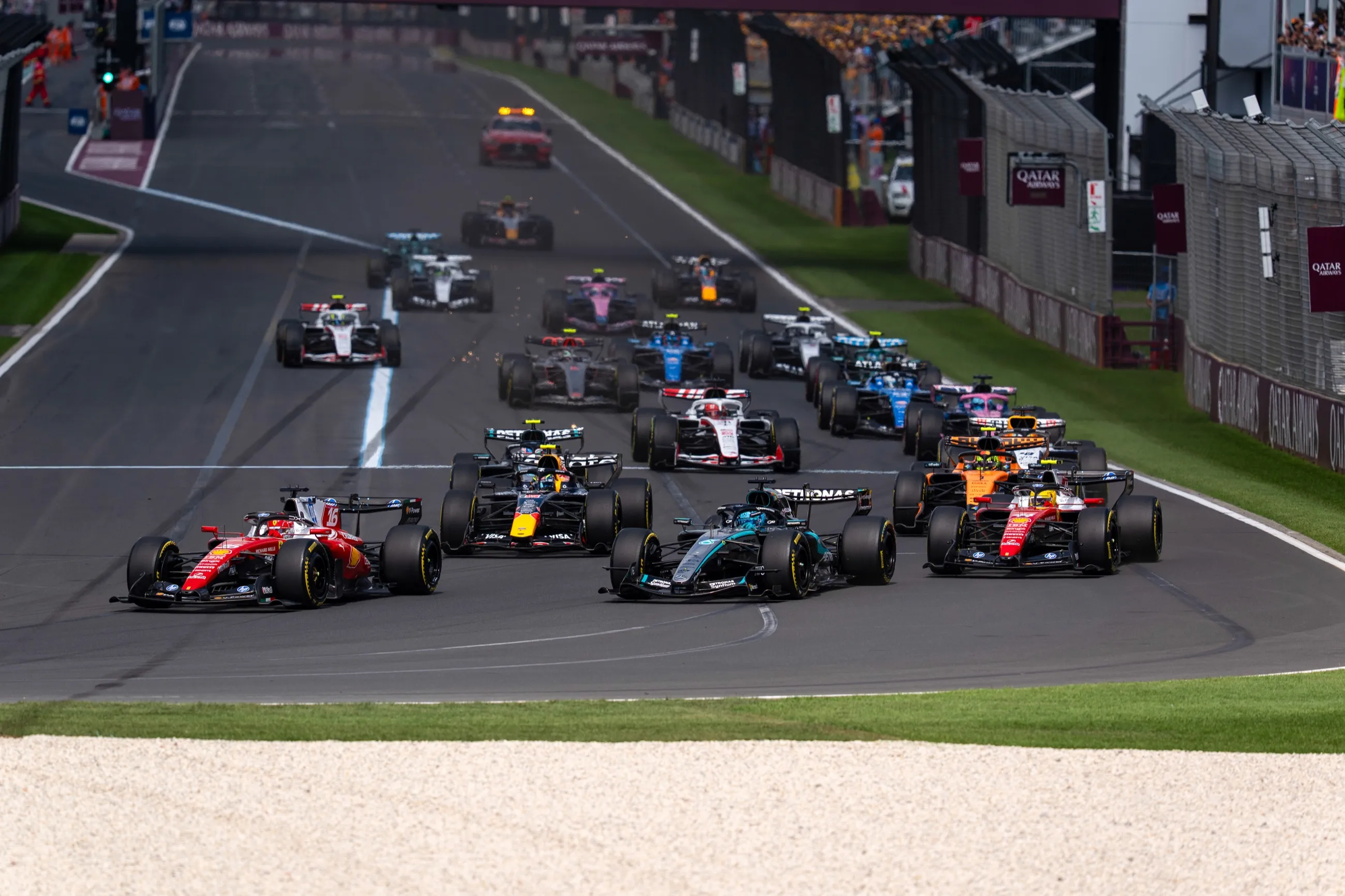 the whole field streams towards the first corner at the start of a race, a ferrari in front